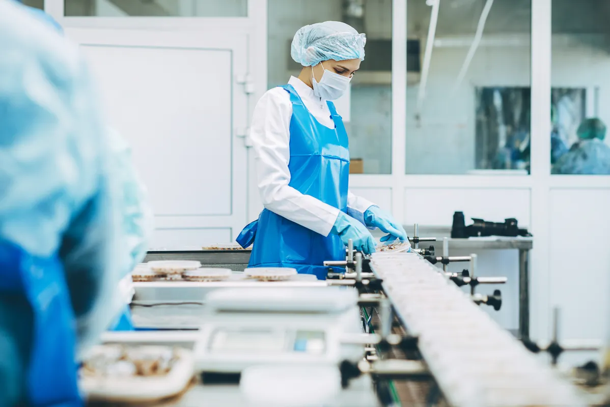En person iført hansker og beskyttelsesbekledning på en fabrikk