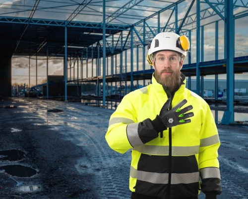En person som som står i ett delvis bygd område med TEGERA® hansker på hendene