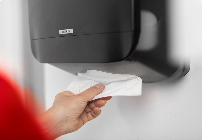 En person som tar ett papirhåndkle fra en dispenser